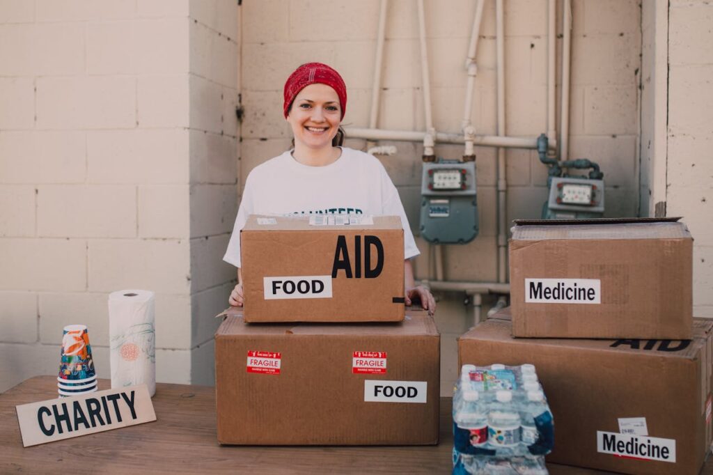 Woman volunteer distributing aid packages with food and medicine for charity outdoors.