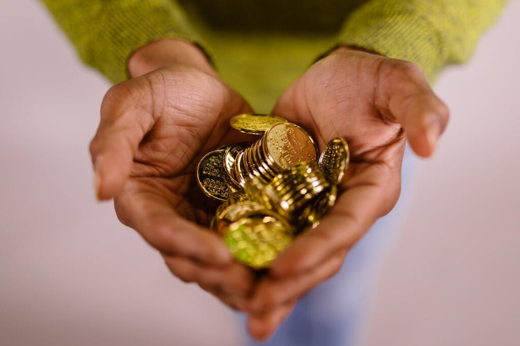 Close-up of hands cupping shiny gold coins, symbolizing wealth and prosperity.